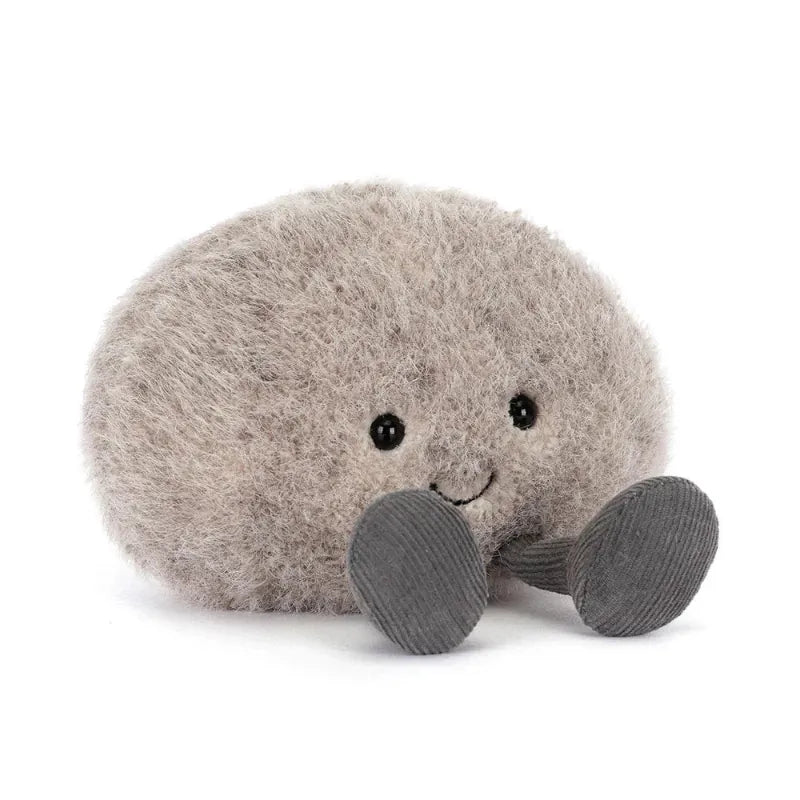 Jellycat Amuseables Pebble angled front view — round grey plush pebble with fluffy textured fur, embroidered smiling face and dark grey corduroy feet showing full rounded shape