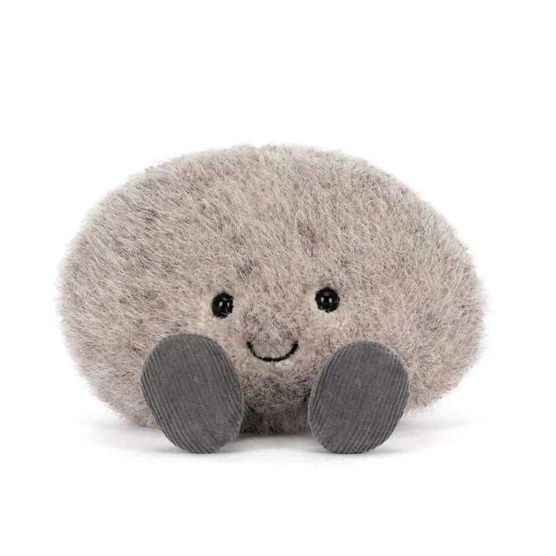  Jellycat Amuseables Pebble front view — flat oval grey plush pebble with fluffy textured fur, embroidered smiling face and small dark grey corduroy feet