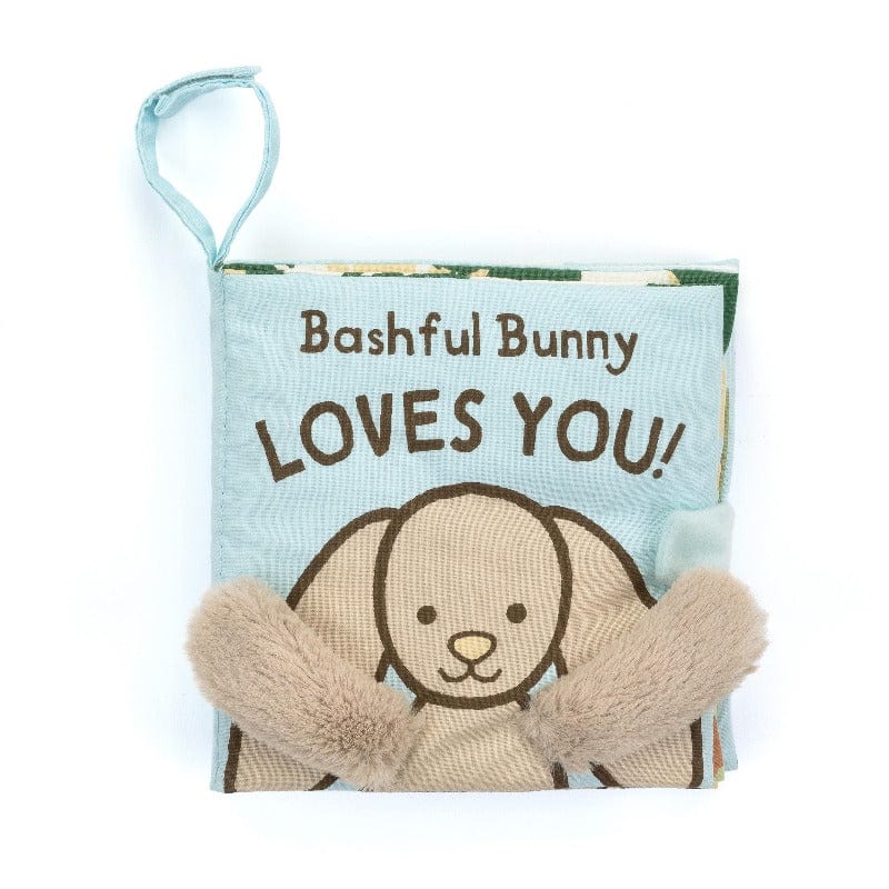 Jellycat Bashful Bunny Loves You Book front cover — soft blue fabric book with 'Bashful Bunny Loves You!' title, embroidered beige bunny face peeking over the bottom edge with fluffy floppy ears, and blue loop hanging tag