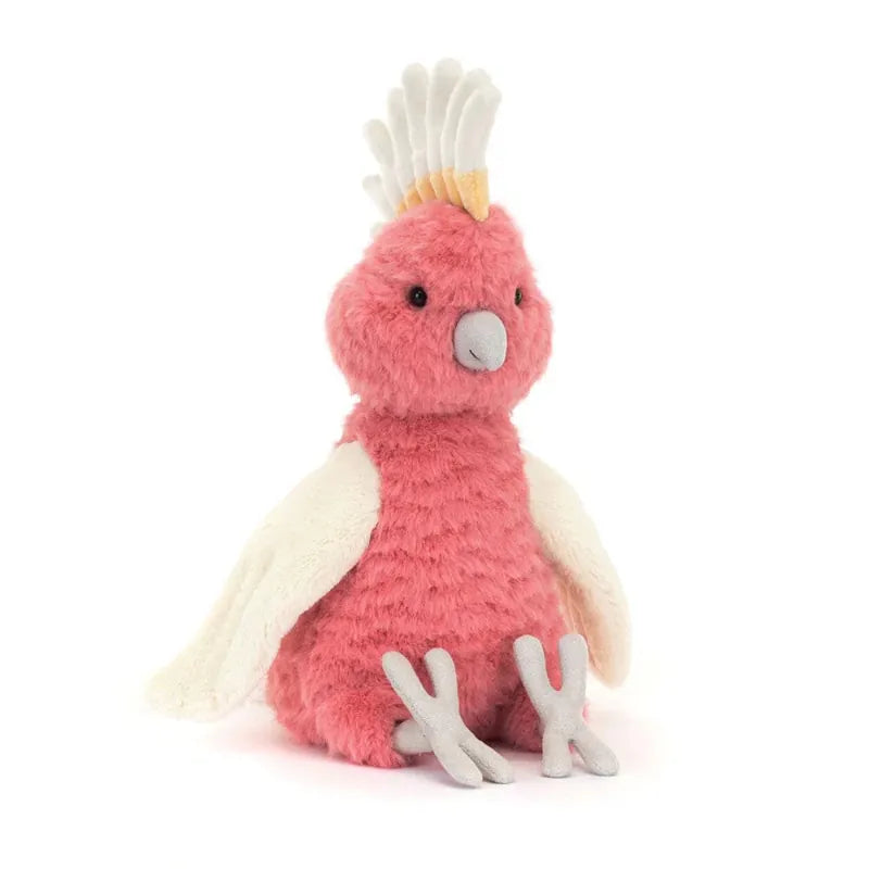 Jellycat Squawkatoo front view — coral pink plush cockatoo with white and yellow crest, grey beak, cream wings spread wide and grey three-toed feet, sitting soft toy